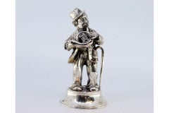 Silver musician standing playing a horn on a circular beaded base