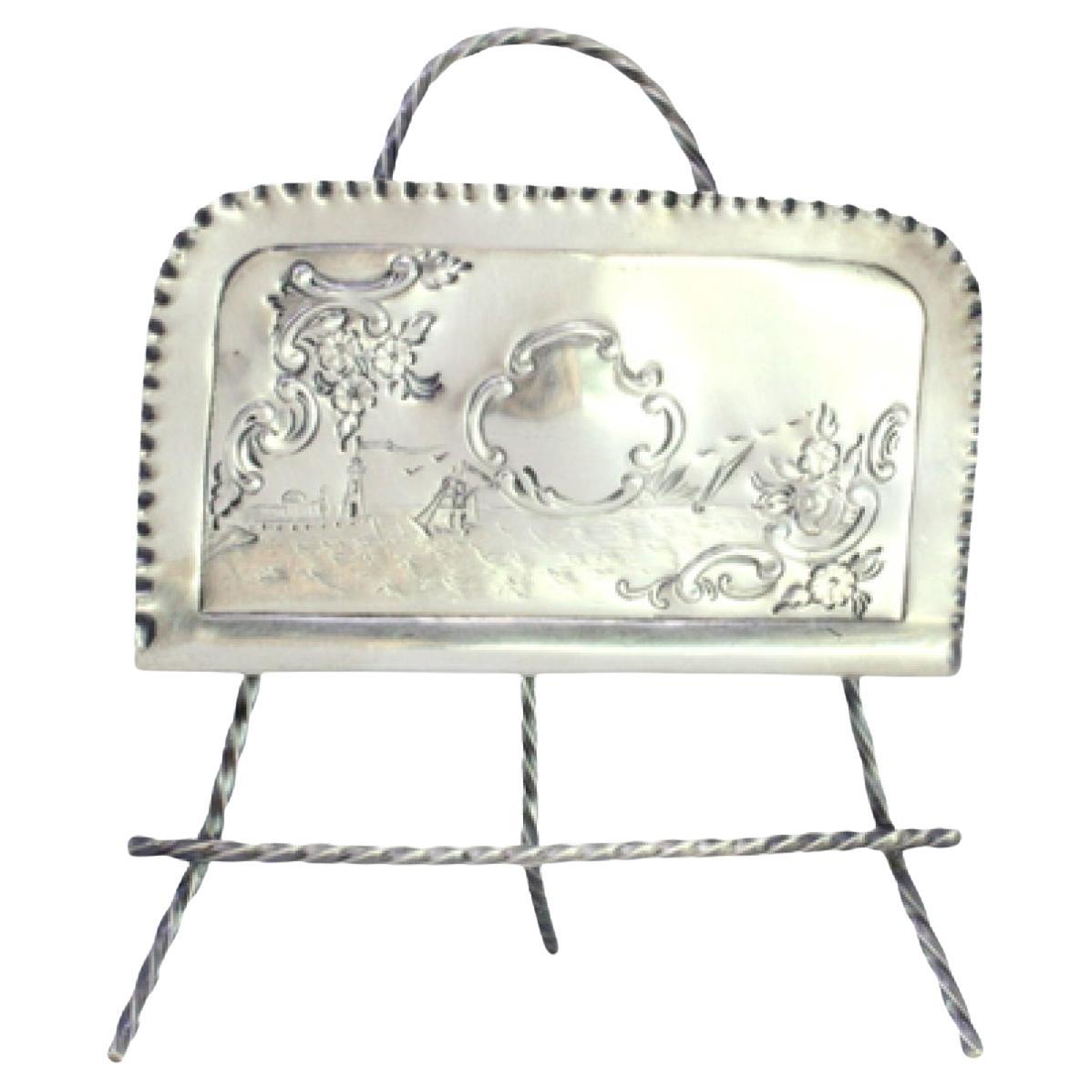 Silver napkin holder with engraved maritime motifs and set on three feet For Sale