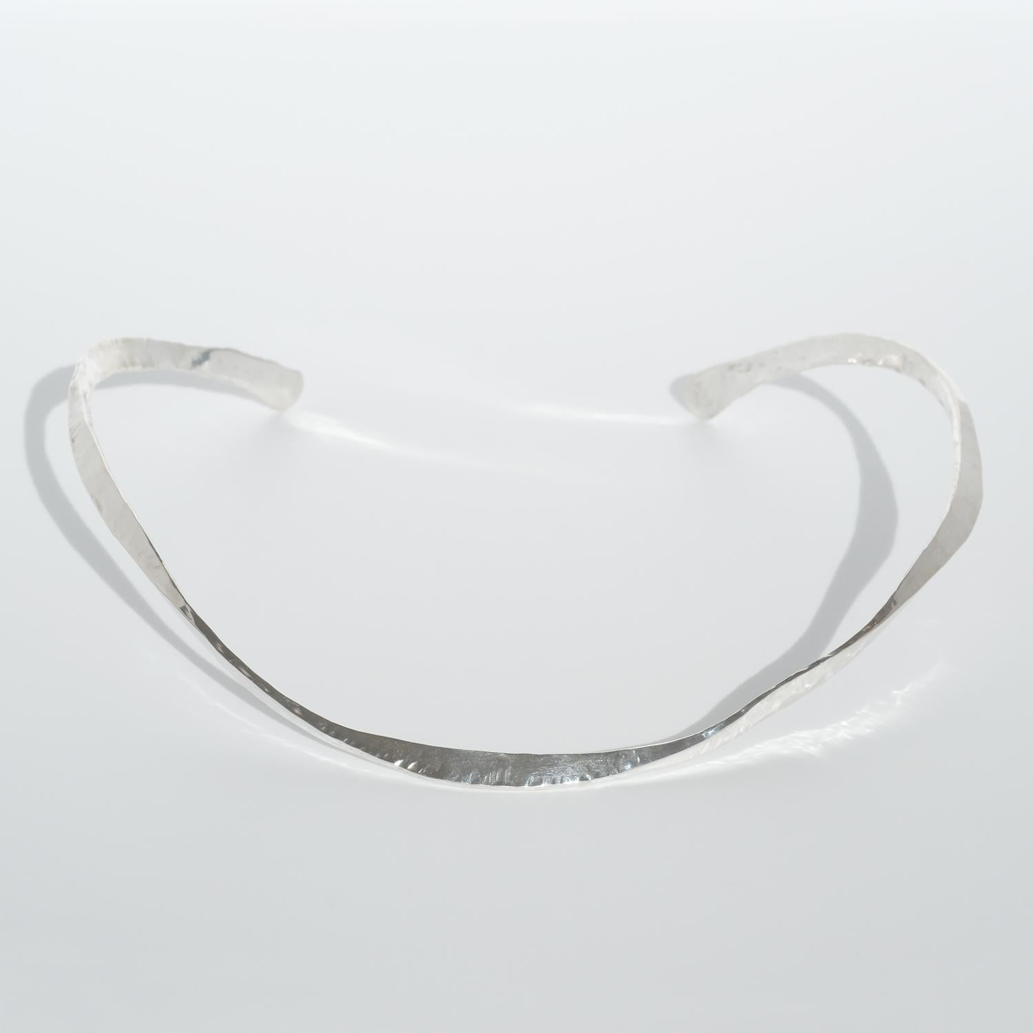 Dieser Halsring aus Silber hat eine schöne, glänzende, bearbeitete Oberfläche. Die Form des Halsrings ist insofern besonders, als dass er gedreht ist.

Dieser Halsring ist sowohl für gesellschaftliche Anlässe als auch für die Alltagsgarderobe