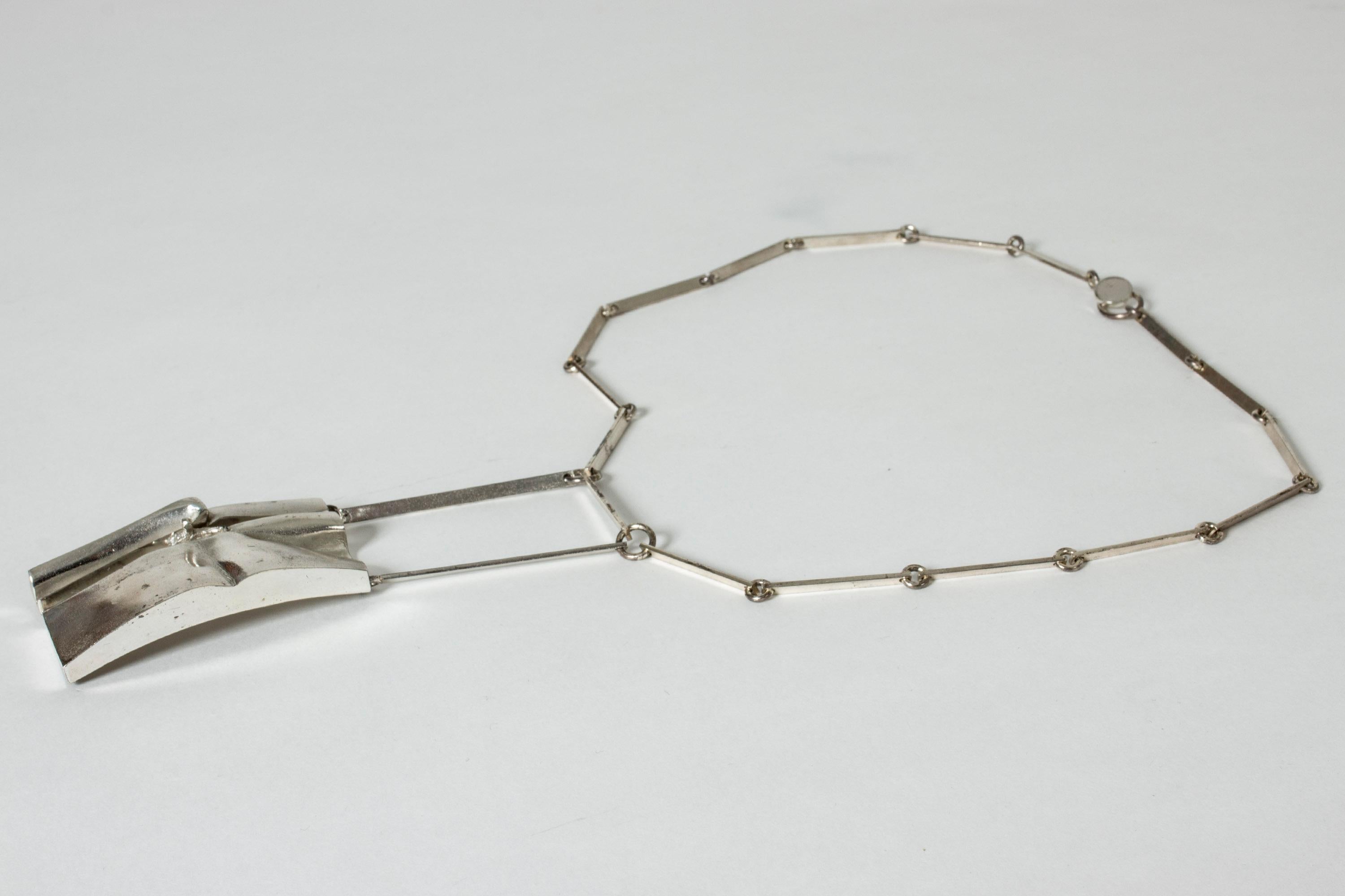Stunning, bold silver necklace by Björn Weckström. A rare design with a robust chain and large pendant with a small human figure peeking up from a “crack”.