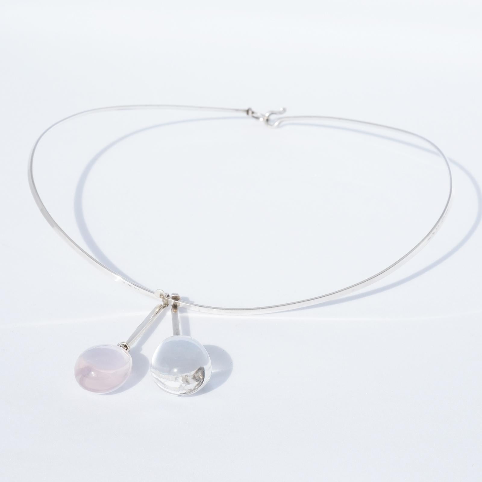 This silver neck ring has a rose quartz and a rock crystal pendant. The rose quartz has an exquisite gentle pink tone whilst the rock crystal is transparent. The neck ring closes easily with a hasp, and the pendants may be worn together or
