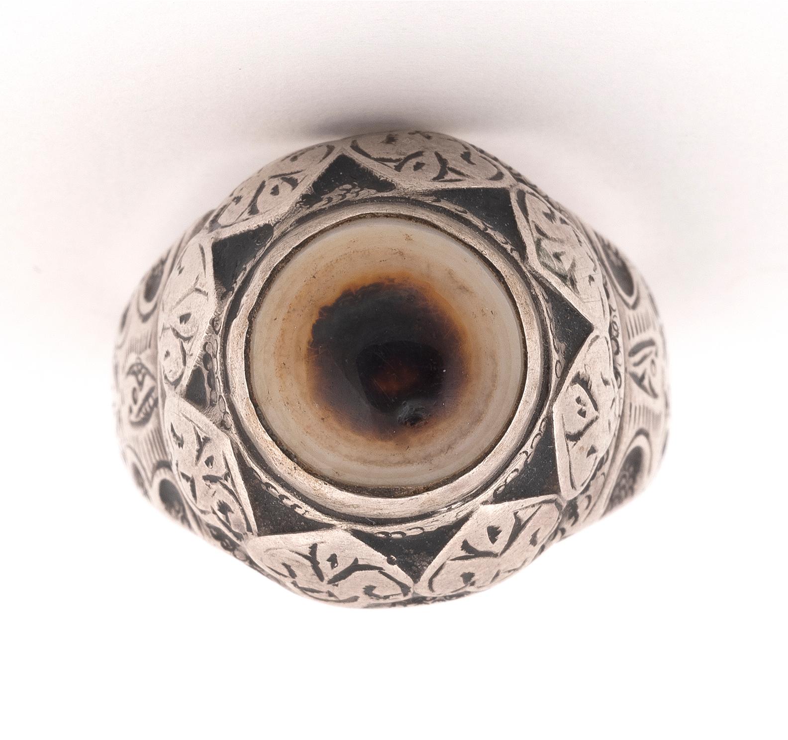 The circular banded agate in foliate engraved twin claw setting to a matching engraved border and tapering hoop, possibly late 16th/early 17th century, finger size 7