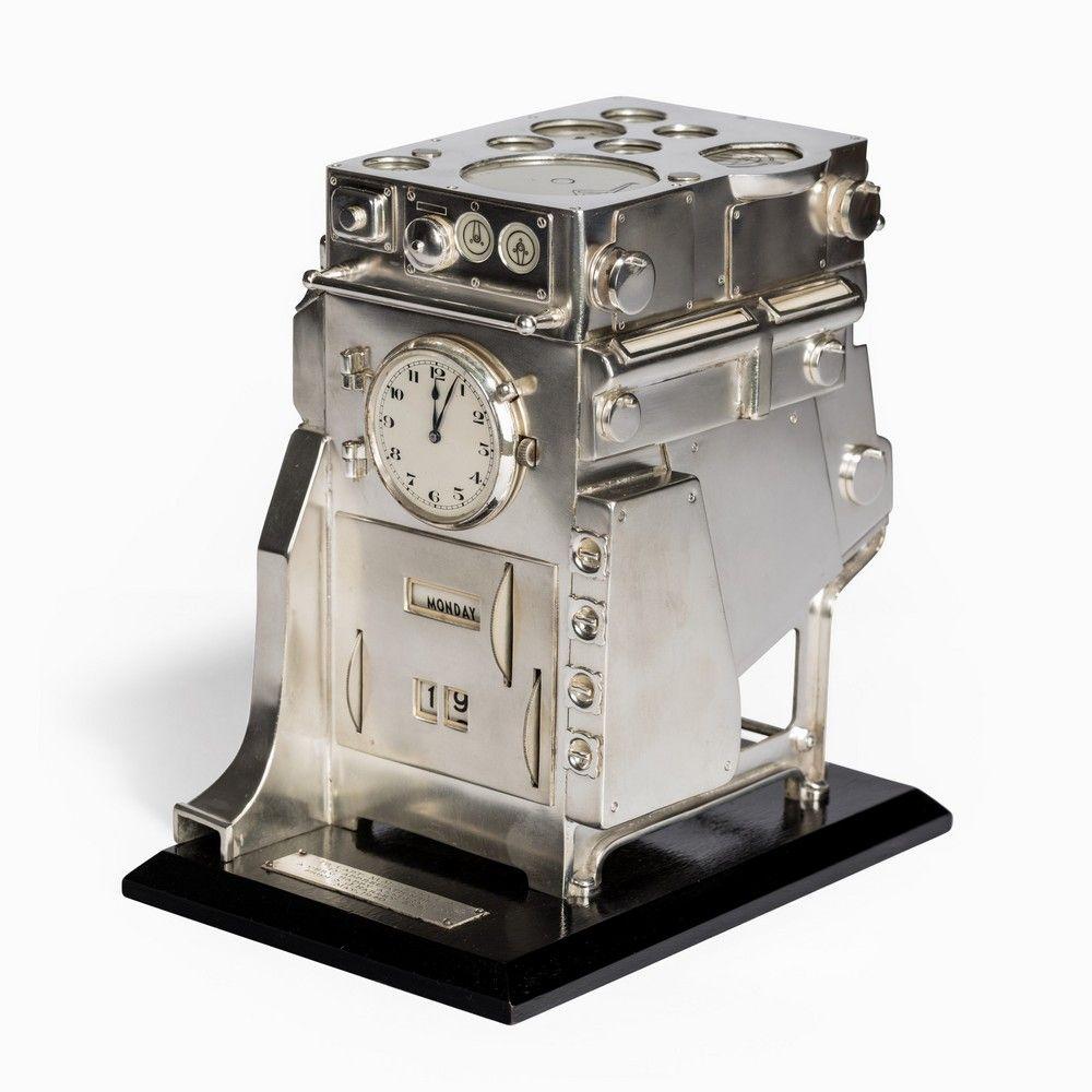An unusual silver novelty perpetual desk calendar and clock, modeled as a ship's boiler, on an ebonized base with plaque inscribed: 