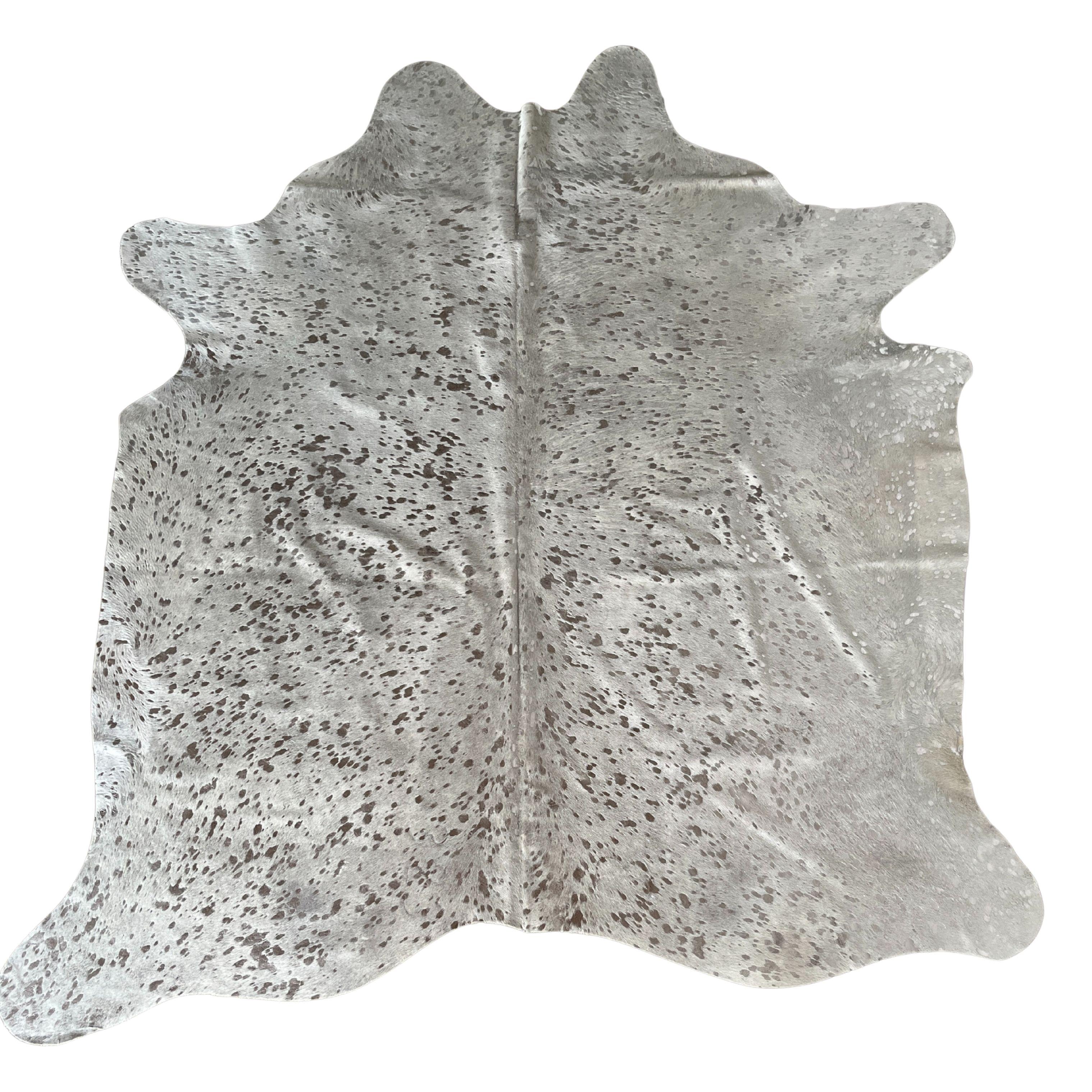 Aporta elegancia moderna a cualquier espacio con esta alfombra de piel metalizada hecha a mano con cuero de vaca natural y acabada en una llamativa paleta de plata sobre blanco. Cada pieza es única, y muestra la belleza orgánica y las variaciones