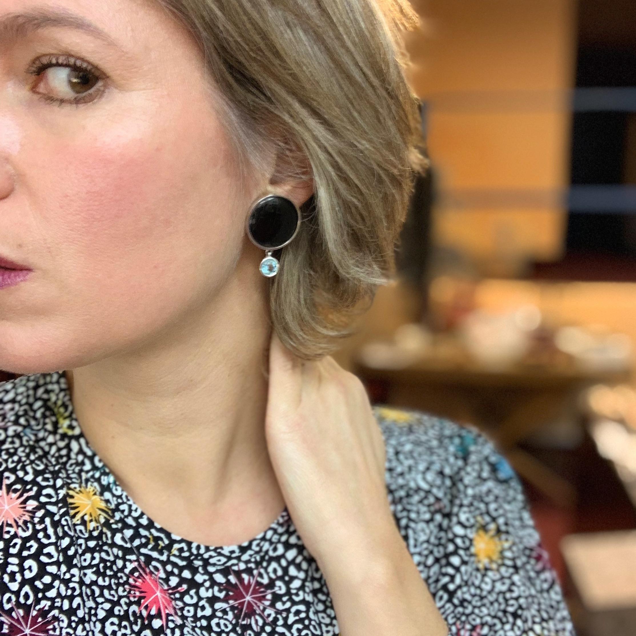 These earrings  are handmade in streling silver with two round onyx pieces that stand on the ear, plus two round aquamarines that hang and have a delicate movement.
The omega clasp allows the earrings to stand perfectly on the ear.
Designed and