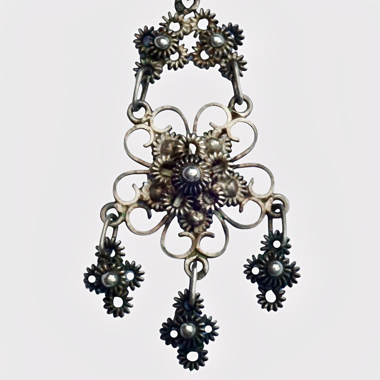 Beautiful silver drop earrings, featuring ornate filigree work. They have hallmarks on the loops that hold the middle drops, and on the earrings stems, the marks are probably continental. We have given the earrings a light clean.

Measuring length