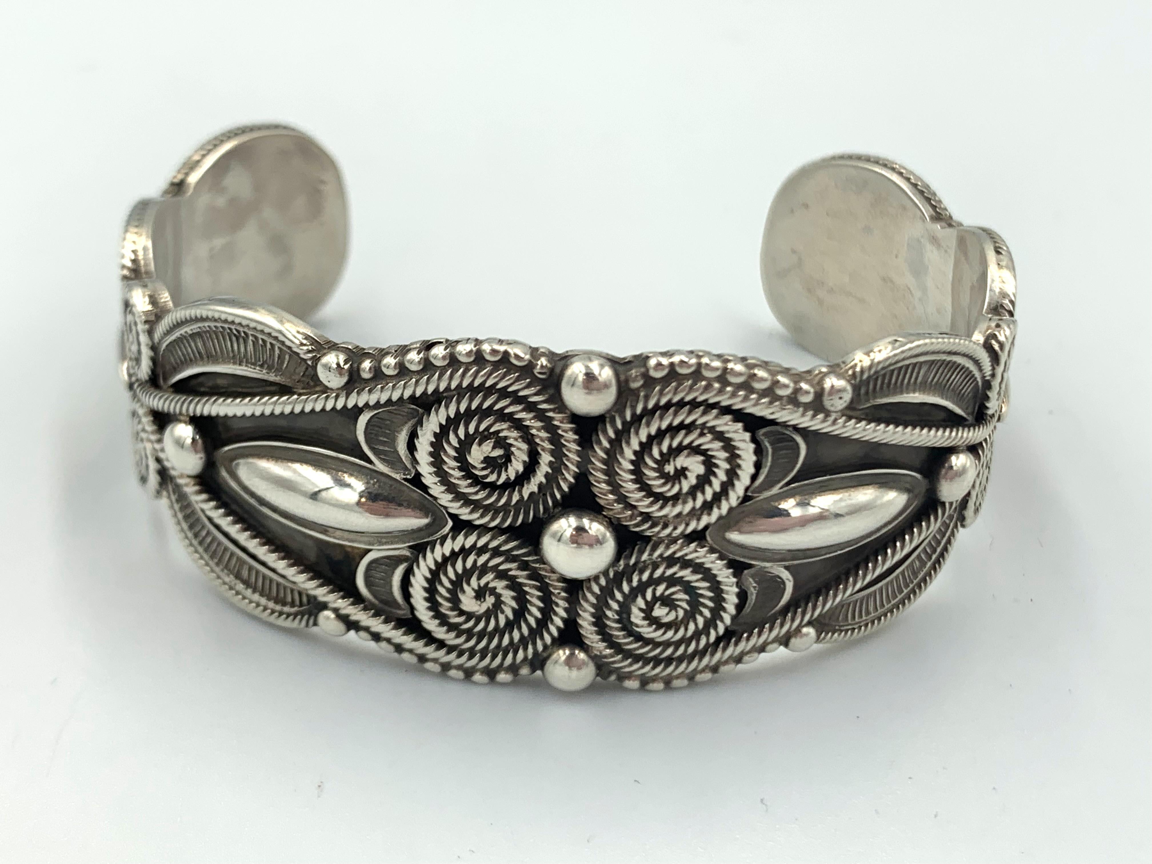 Brazalete de plata de ley del orfebre navajo Rick Martínez. El puño de 2,5 cm tiene varios tamaños de gotas de lluvia, alambre trenzado y superposición estampada.  Rick combina patrones tradicionales con técnicas contemporáneas.  El interior de la
