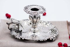 Silver paddle with embossed floral motifs and a monogrammed card on the handle