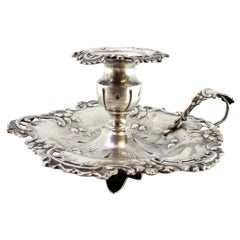 Silver paddle with floral motifs in relief and set on three flower-shaped feet