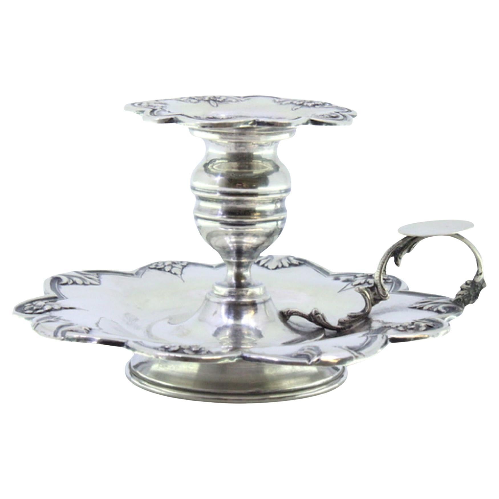 Silver paddle with raised floral motifs and placed on a circular base