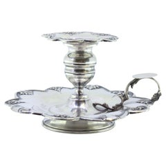 Silver paddle with raised floral motifs and placed on a circular base