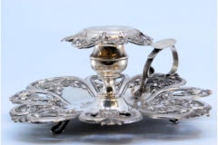 Silver paddle with raised floral motifs and resting on three feet