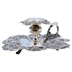 Silver paddle with raised floral motifs and resting on three feet