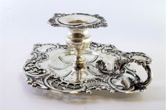 Silver paddle with reliefs surrounding a monogram card and resting on three feet