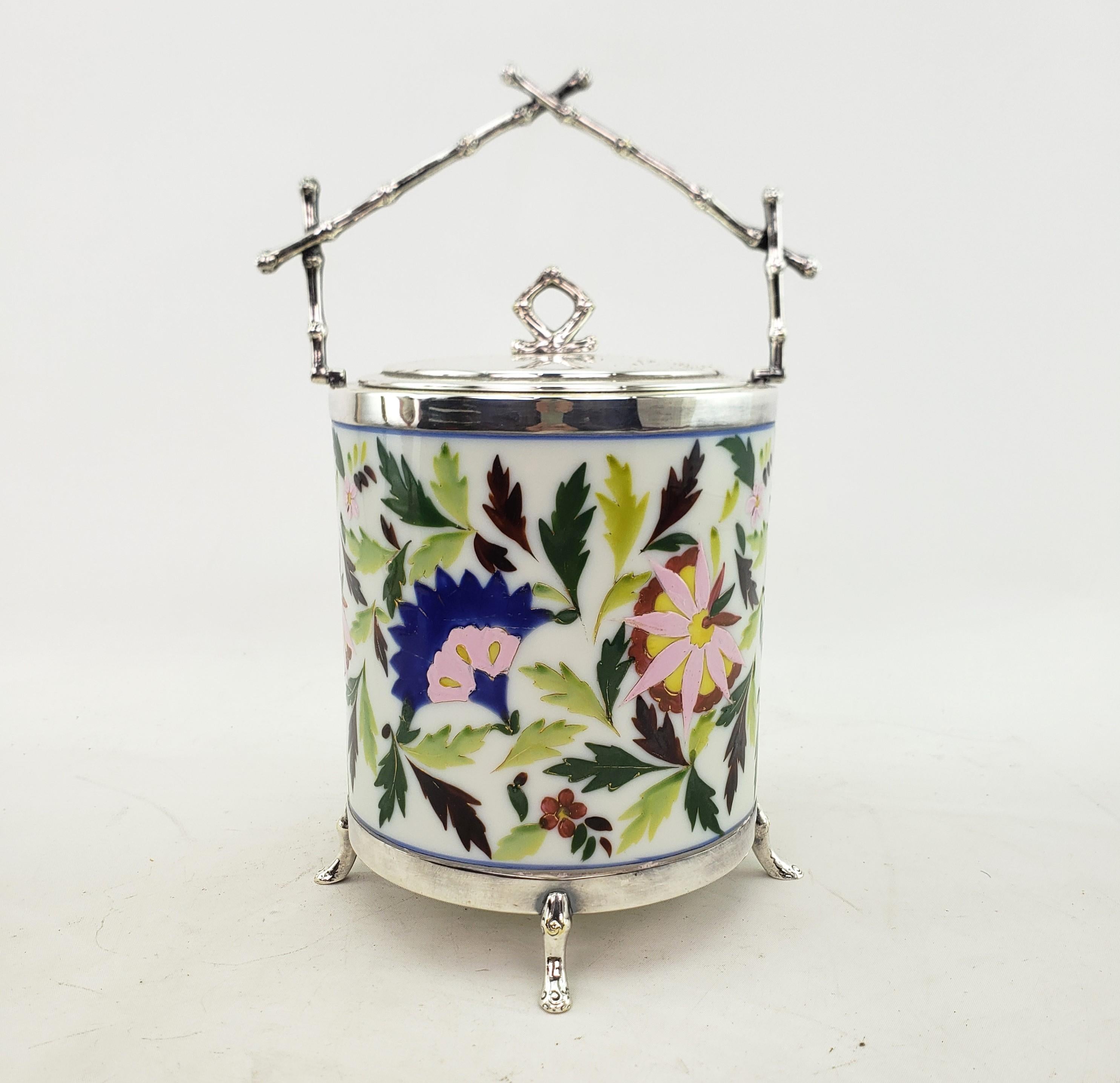 This antique biscuit barrel is unsigned, but presumed to have originated from England and date to approximately 1920 and done in the Art Deco style. The biscuit barrel is composed of a ceramic cylindrical with hand-painted floral decoration and