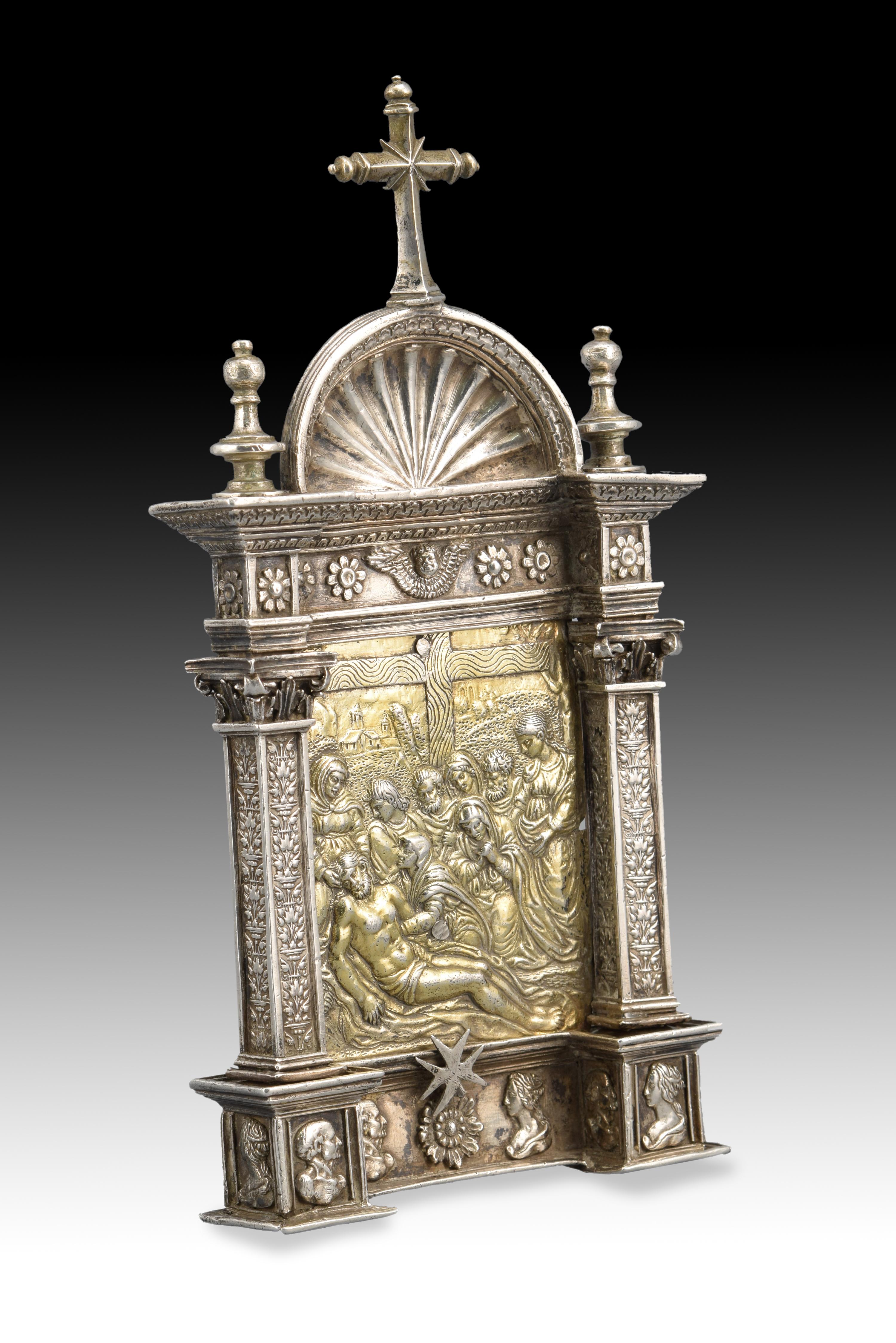 Portapaz. Silver in its color and gilded. Century XVI. 
 Portapaz made of silver that has a handle (decorated with delicate plant motifs similar to those of the pilasters) and a female and a male bust at the bottom, as well as other architectural