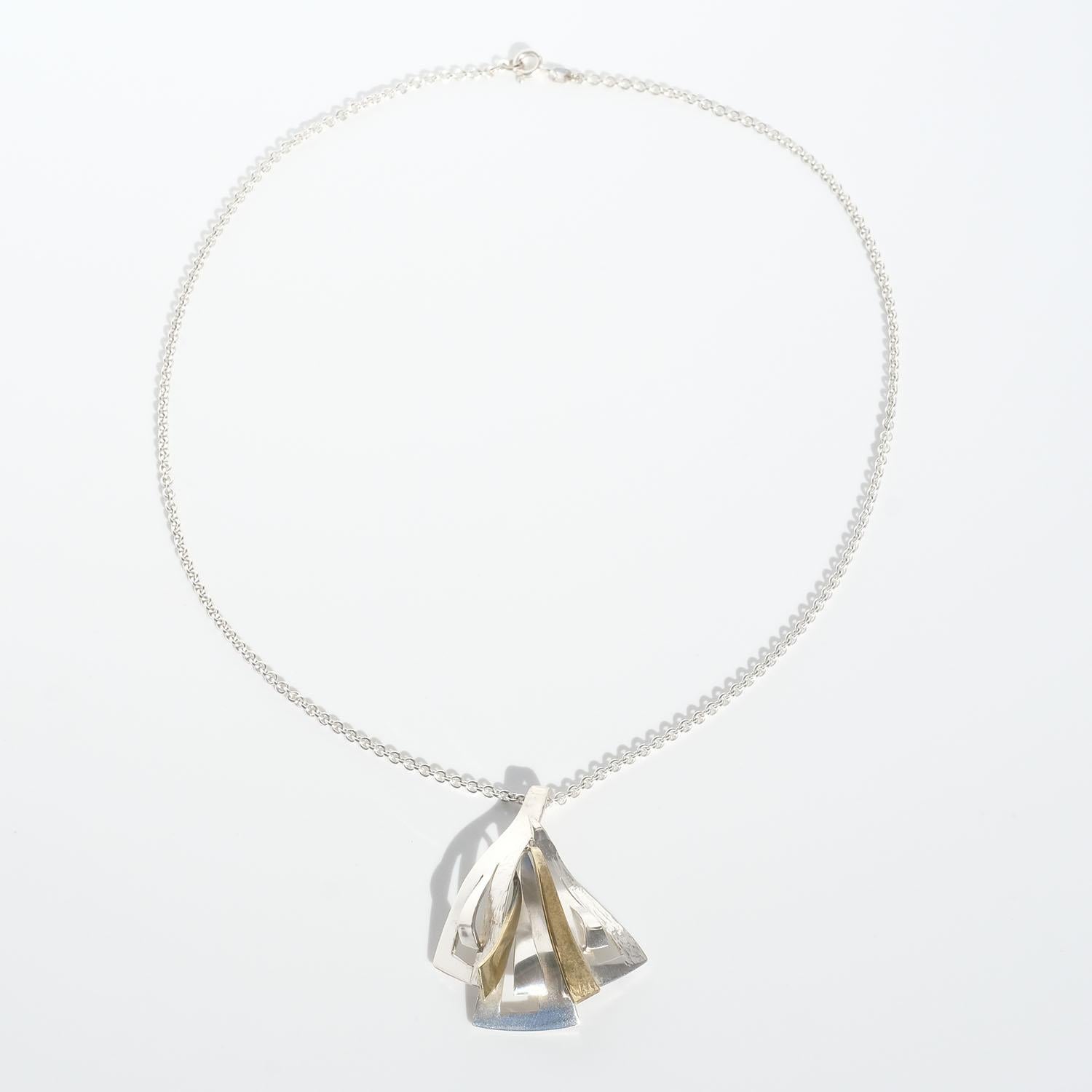 This sterling silver pendant has an undulating shape. It has both a shiny and a patterned suface, and in the center it is partly gilded. With the pendant comes a 46,5 cm long silver cable chain.

The pendant is perfect for the everyday wardrobe and