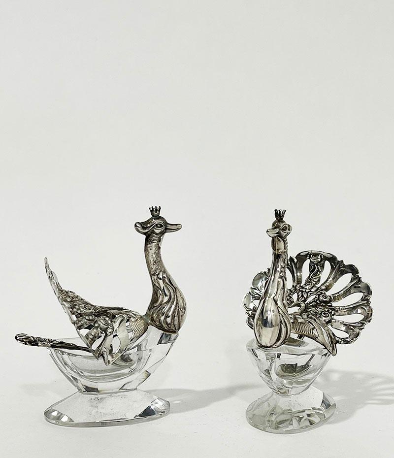 Silver pepper and salt cellars in the shape of a peacock

A lovely silver with crystal cellars in the shape of a peacock with open feathers with rose motif, including 2 small silver spoons with rose motif. 
The peacocks are marked with the silver