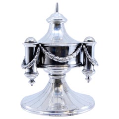 Silver perfume bottle with round base and cord application around the edge