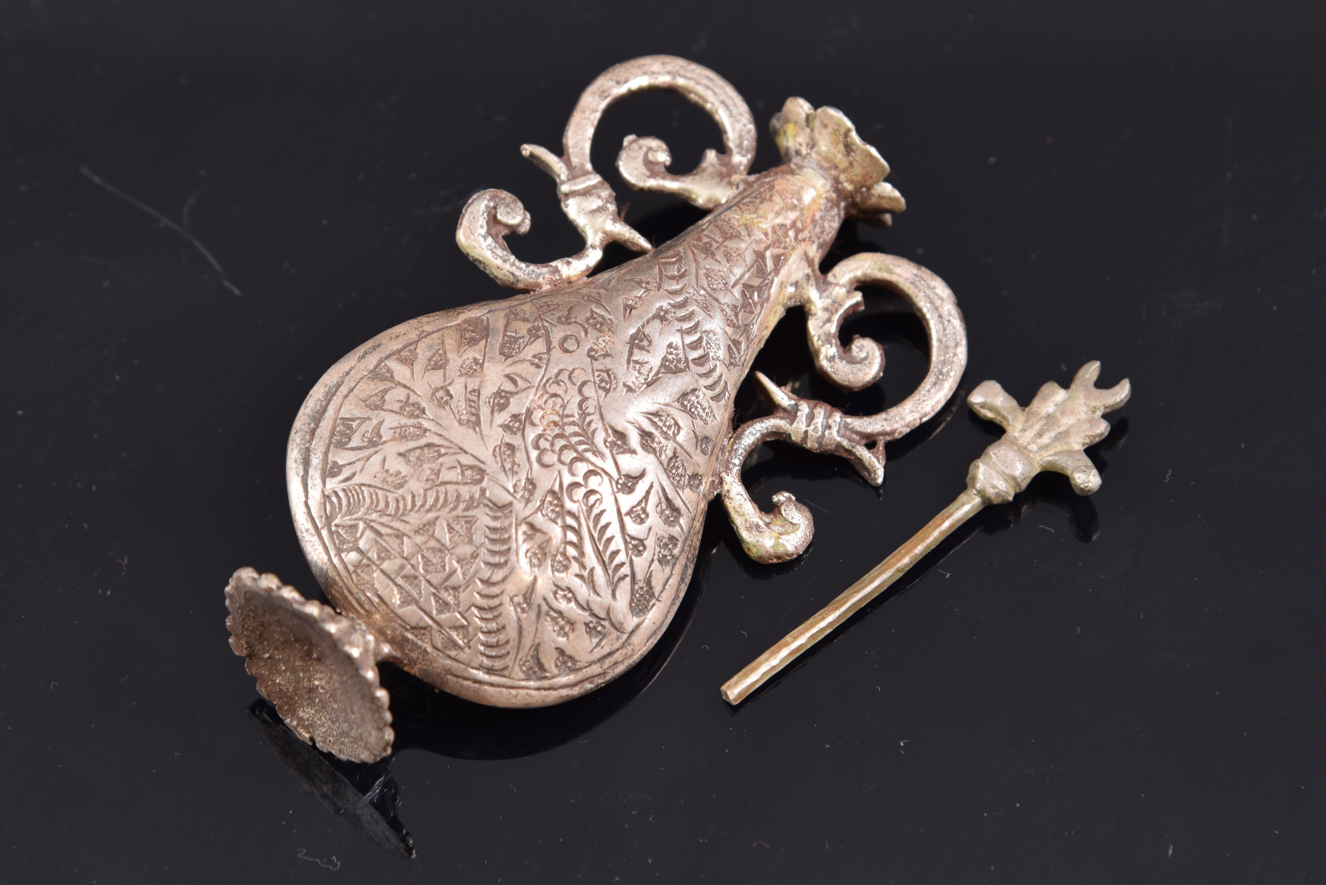 Silver perfume box. 19th century.

 Teardrop-shaped bottles with feet, elaborate handles decorated with vegetal elements and scrolls of Classicist influence, and caps with flowers and leaves. On the outside of the body, the perfume bottles are