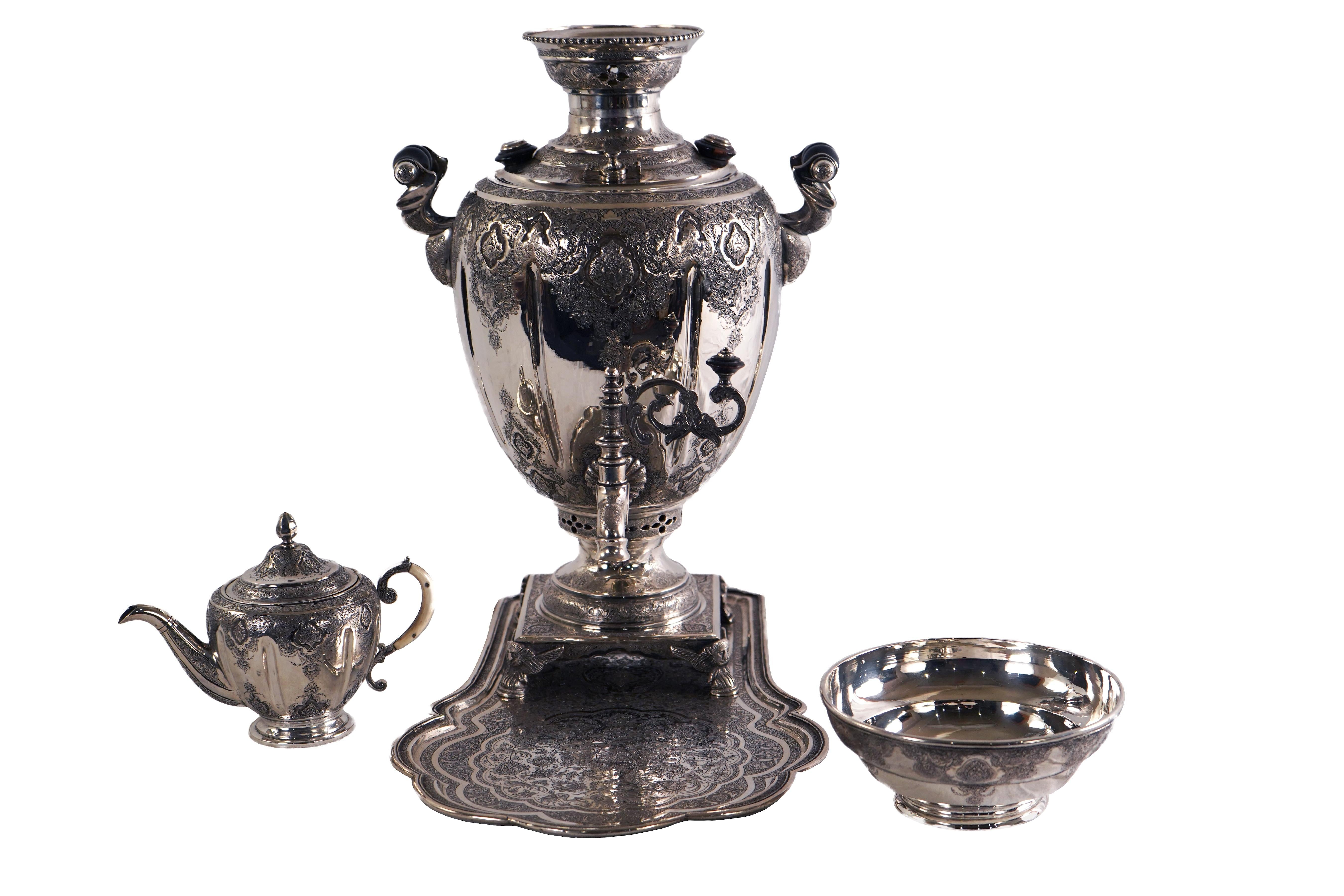 Persian Silver Samovar set with carved wood handles and knobs, a teapot with carved handle, a pedestal waste bowl, and a fitted tray with shaped edge. Decorated with birds, scrolling foliate, and cartouche with shaped edges. Each item is stamped,