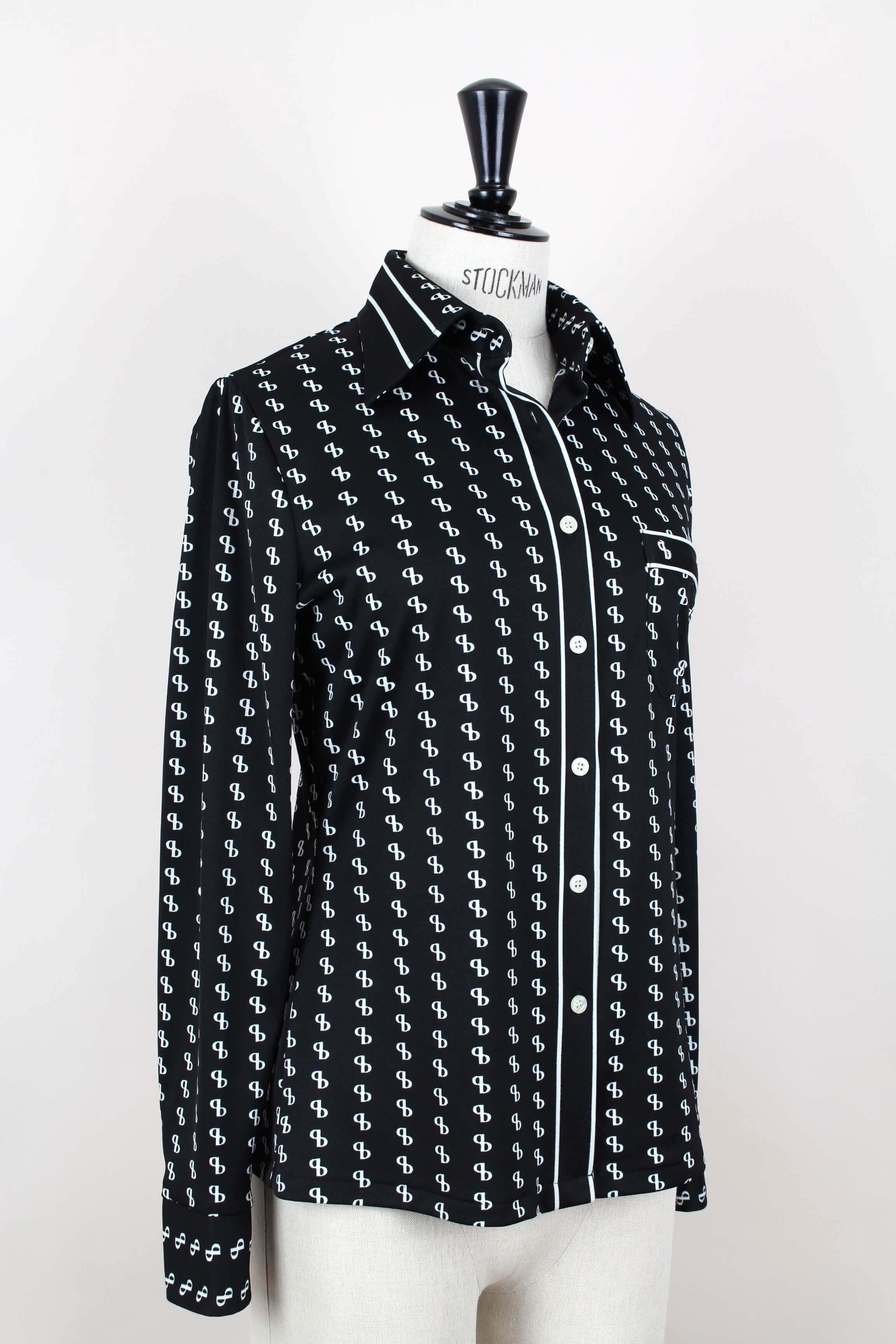 Smart 1970’s Silver Piano black jersey blouse with an eye-catching white monogram print. The design features a slightly fitted silhouette, a pointed collar, long buttoned sleeves, a chest patch pocket and a front button closure. Love the sleek