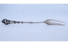 Silver pickle fork with two prongs and bird-decorated raised handle