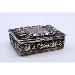 Silver pill box decorated with flower reliefs on the hinged lid