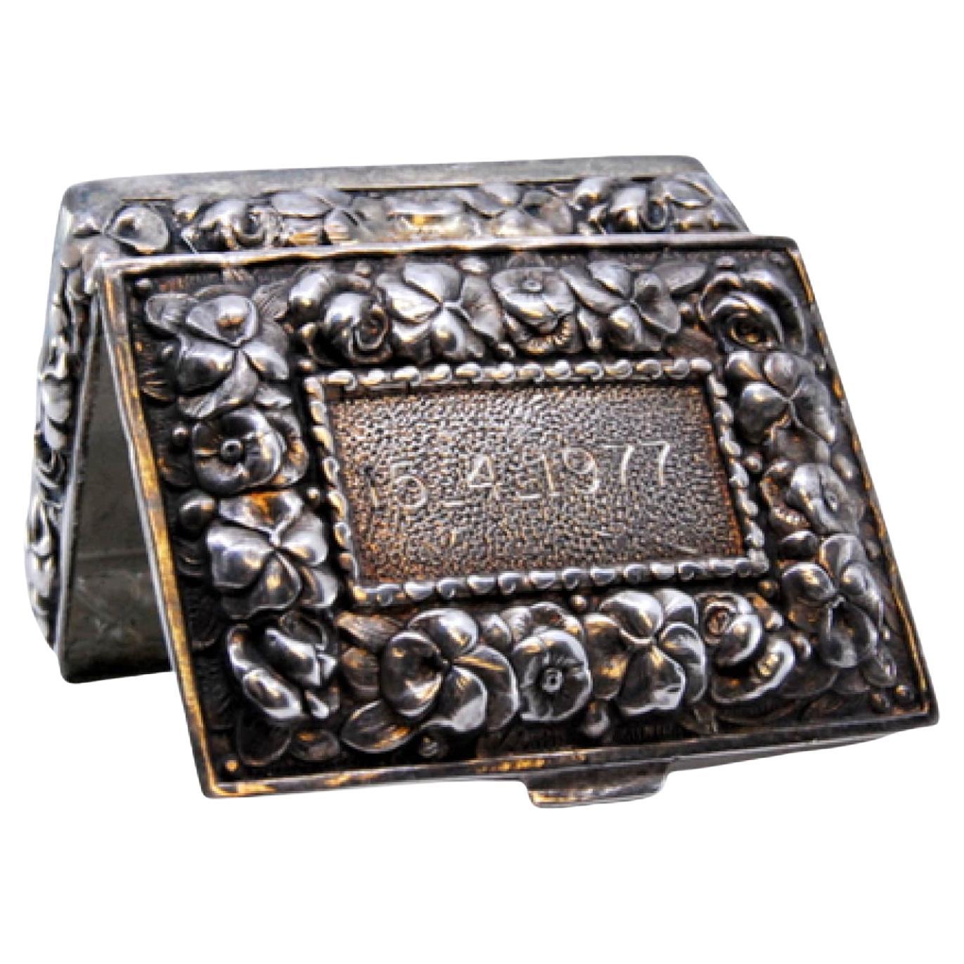 Silver pill box decorated with flower reliefs on the hinged lid