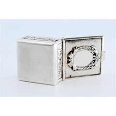 Silver pill box with bows and reliefs on the edge and hinged lid
