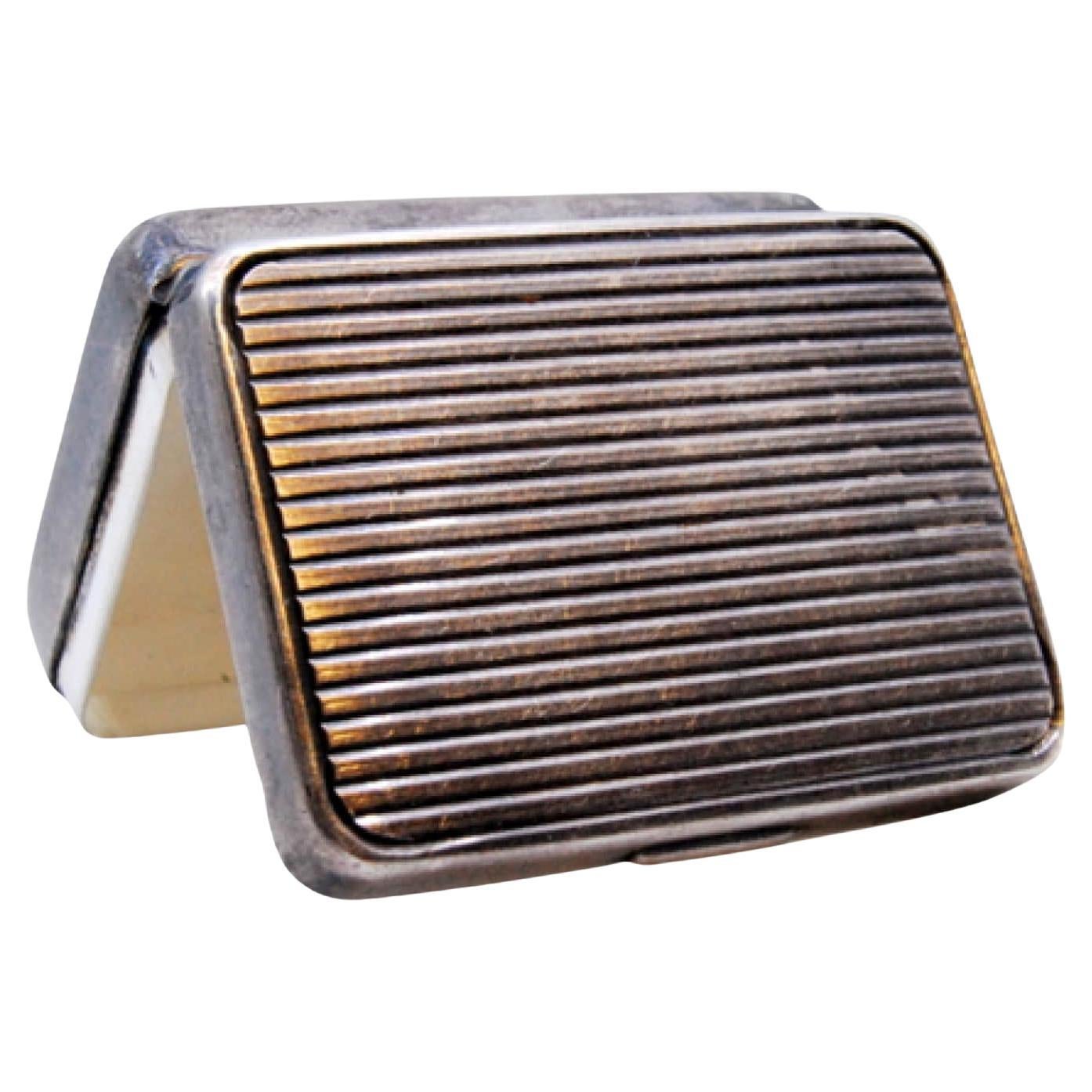 Silberne Pillendose mit geriffelten Kanten entlang des Scharnierdeckels