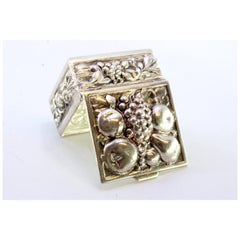 Silver pill box with fruit revealed on the hinged lid
