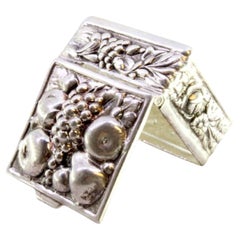 Silver pill box with fruit revealed on the hinged lid