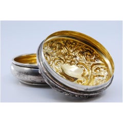 Silver pill box with gold interior and relief on the removable lid