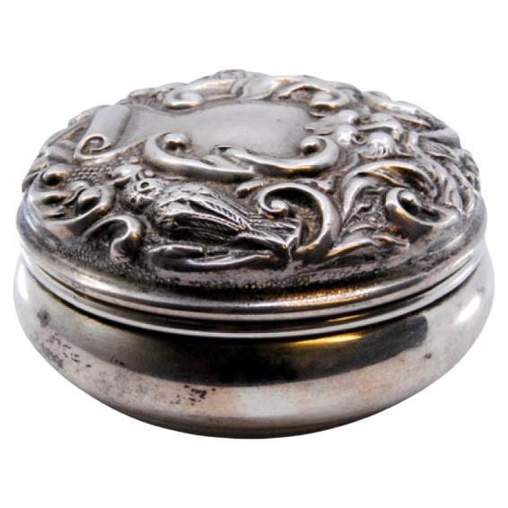 Silver pill box with gold interior and relief on the removable lid