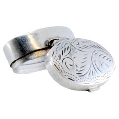 Silver pill box with plant motifs engraved on the hinged lid
