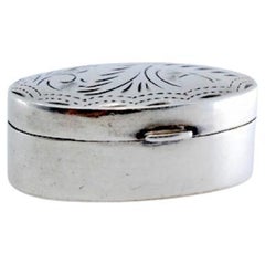 Silver pill box with plant motifs engraved on the hinged lid