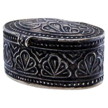 Silver pill box with relief decoration on the hinged lid