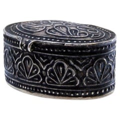 Silver pill box with relief decoration on the hinged lid