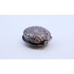 Silver pill box with reliefs on both sides of the hinged lid