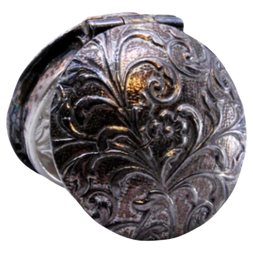 Silver pill box with reliefs on both sides of the hinged lid