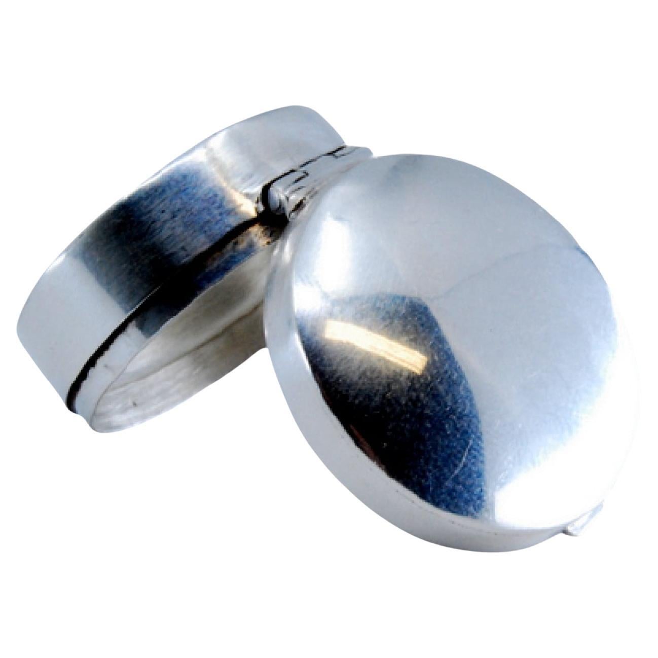 Silver pill box with reliefs on both sides of the hinged lid