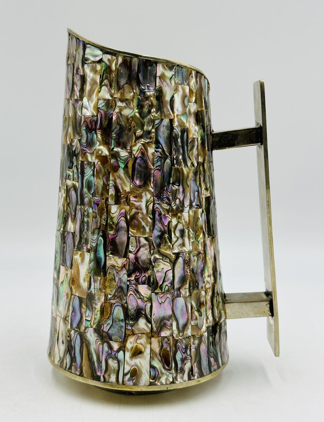 Vintage silver plated water pitcher with abalone shell inlaid designed and manufactured in Mexico in the 1960s
 
More than a utilitarian piece, this pitcher is more of a sculpture, the workmanship and attention to detail is totally stunning.
 
 The