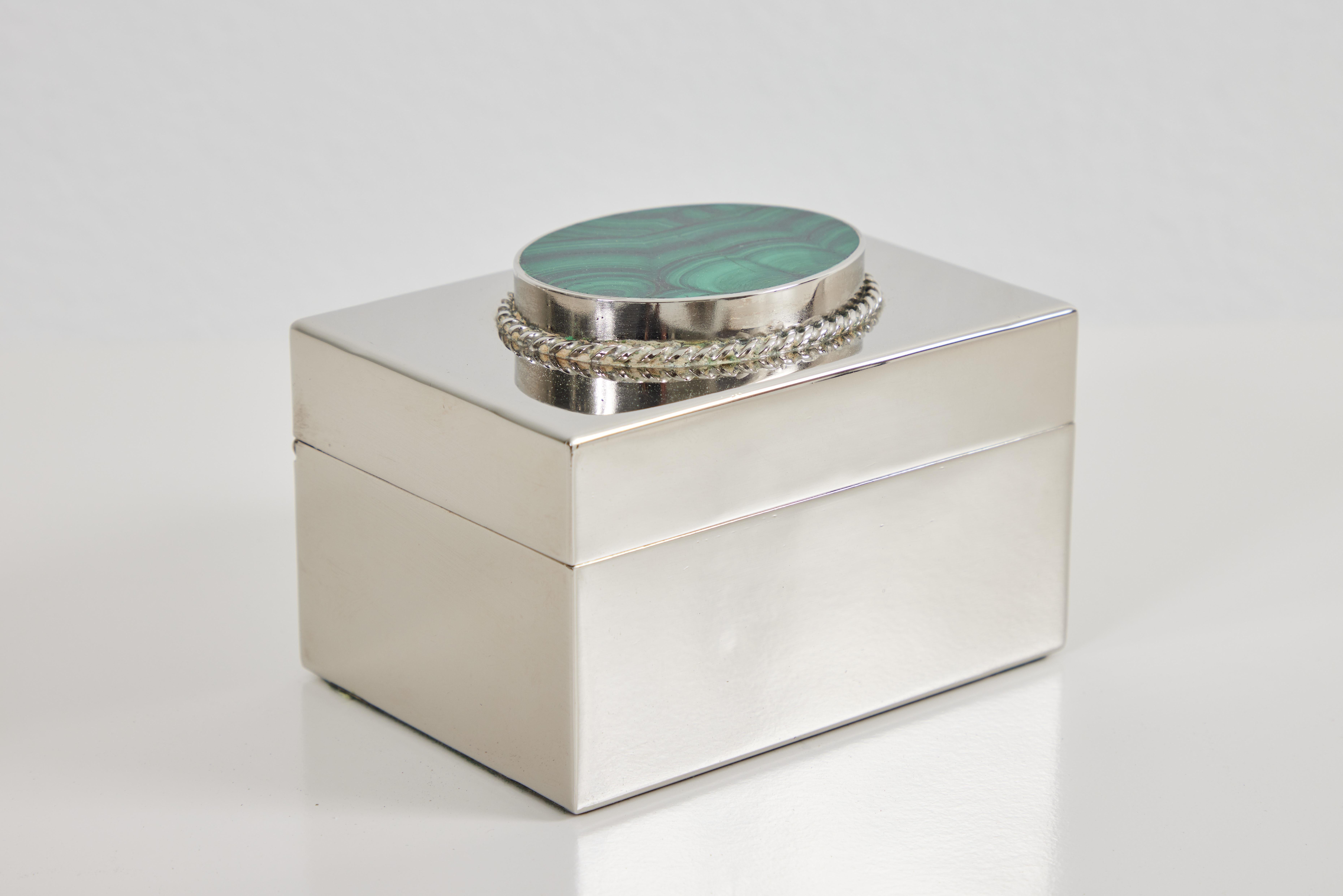 This Antony Redmile lidded box is hinged and is set with an oval piece of malachite on the lid. The inside is lined with a pink velvet. The 'Redmile London'. signature is impressed to the back of the box. 
Antony Redmile was a highly successful