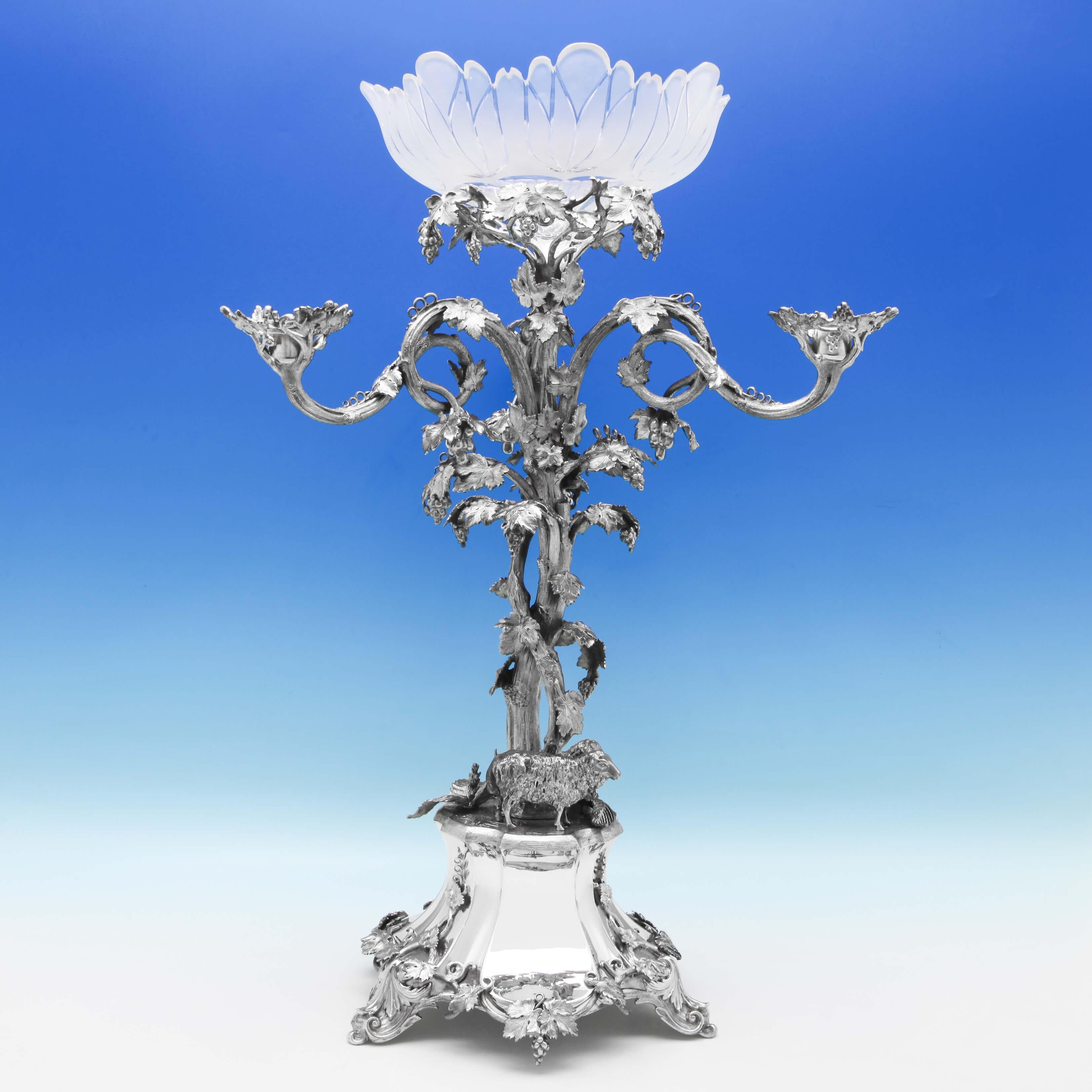 Made circa 1880, this attractive, Victorian, antique silver plated centrepiece, features a central glass bowl, and three smaller side bowls. The centrepiece is naturalistic in style, modelled as an intwined vine under which two sheep are shading