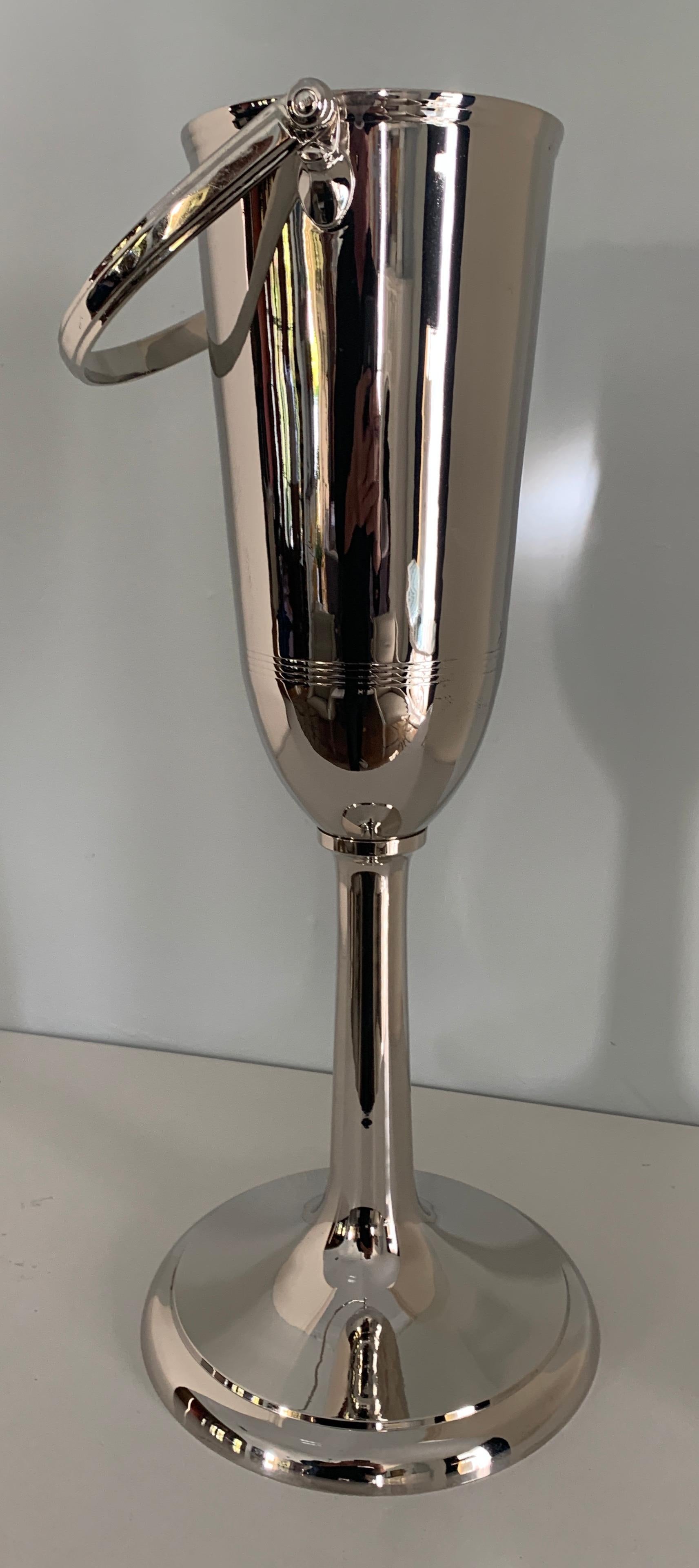 Sophisticated silver plate champagne or wine stand - a table height piece that easily holds your favorite bottle. The piece is newly plated, the architectural design also has and etched linear feature 3/4 down. A handle makes carrying your spirits