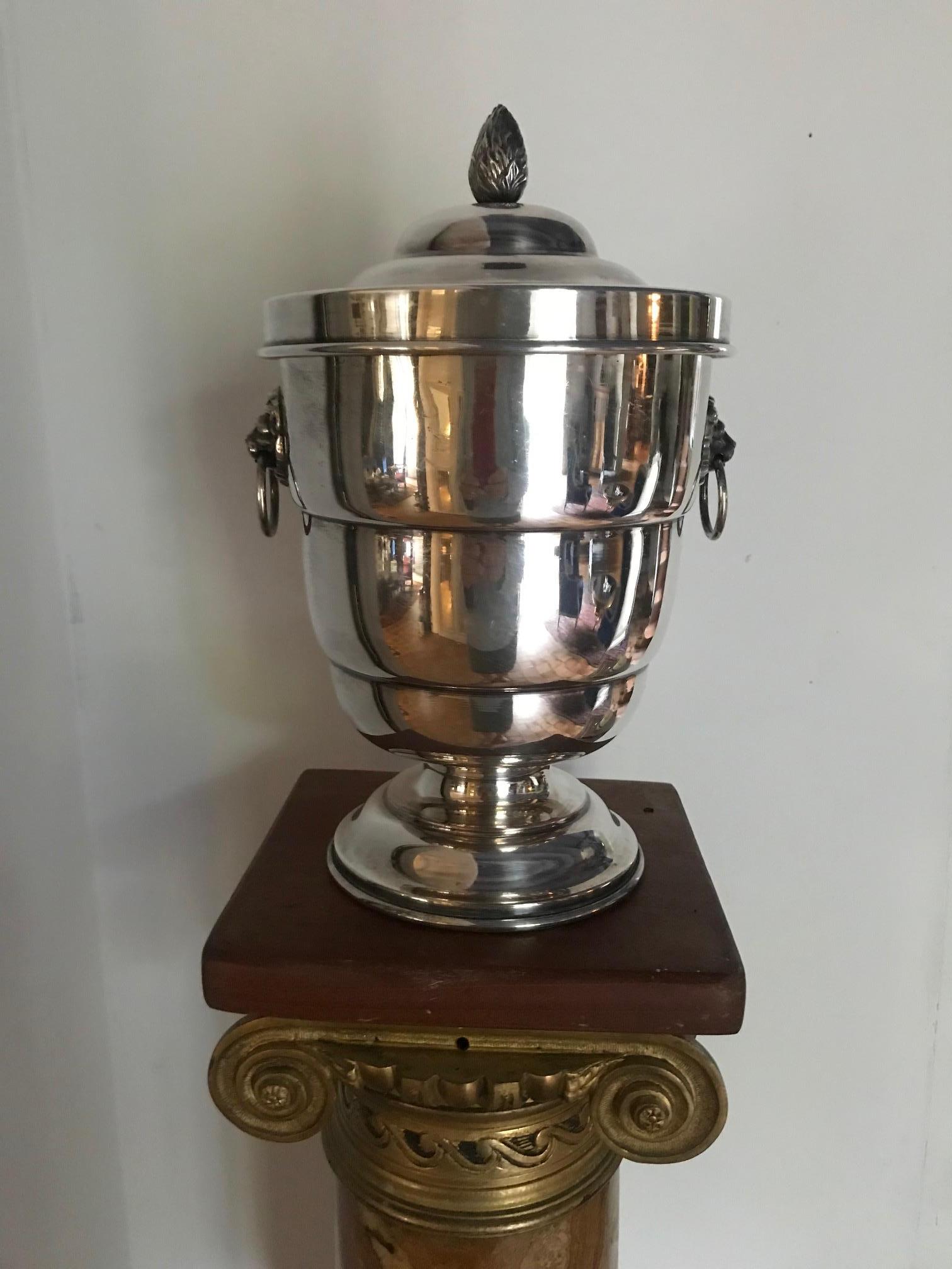 A fantastic quality silver plate English ice bucket. Georgian style with lion head handles and mercury glass lined bucket. The lid is adorned with an acorn. Stamped underneath silver plate.