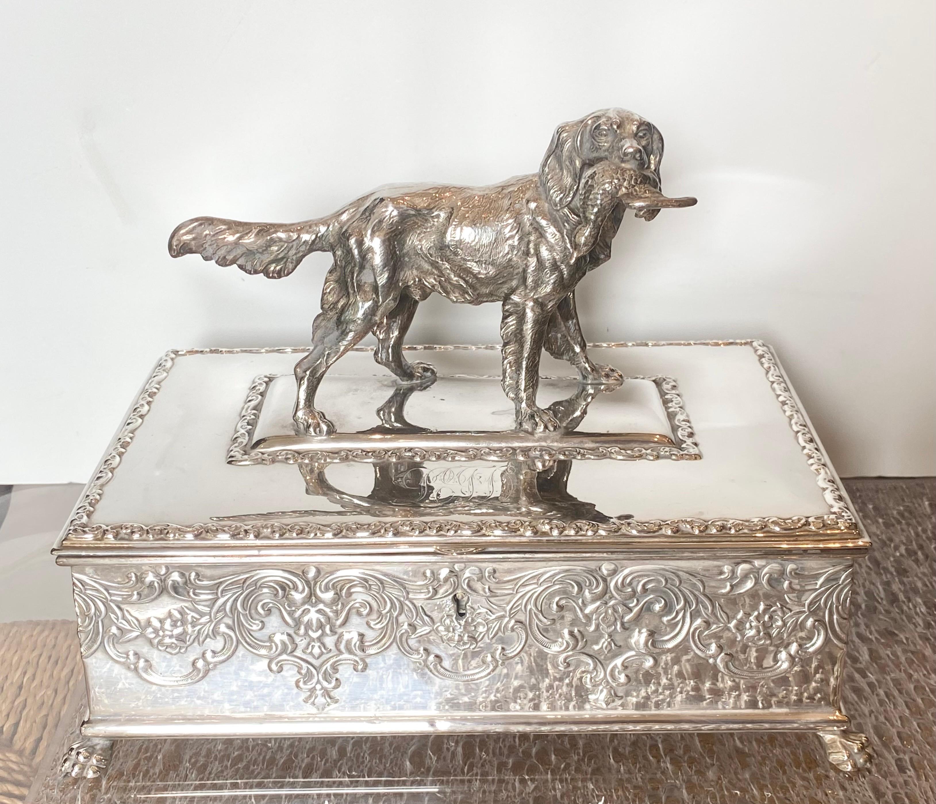 American silver plate humidor, Wilcox Silver Plate Co., Meriden, CT hinged lid with figure of retriever with duck, box with repousse scrolled floral and foliate design and paw feet, monogrammed on lid, marked and numbered on bottom.