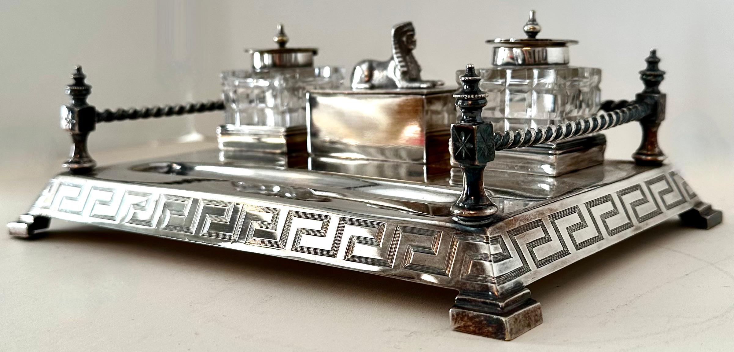 A stunning silver plate ink well with two cut crystal ink wells - both capped with a silver top and greek key trim. A center storage piece is presented with a Sphinx removable lid.

The tray has a gallery and corner feet. 

A stunning piece