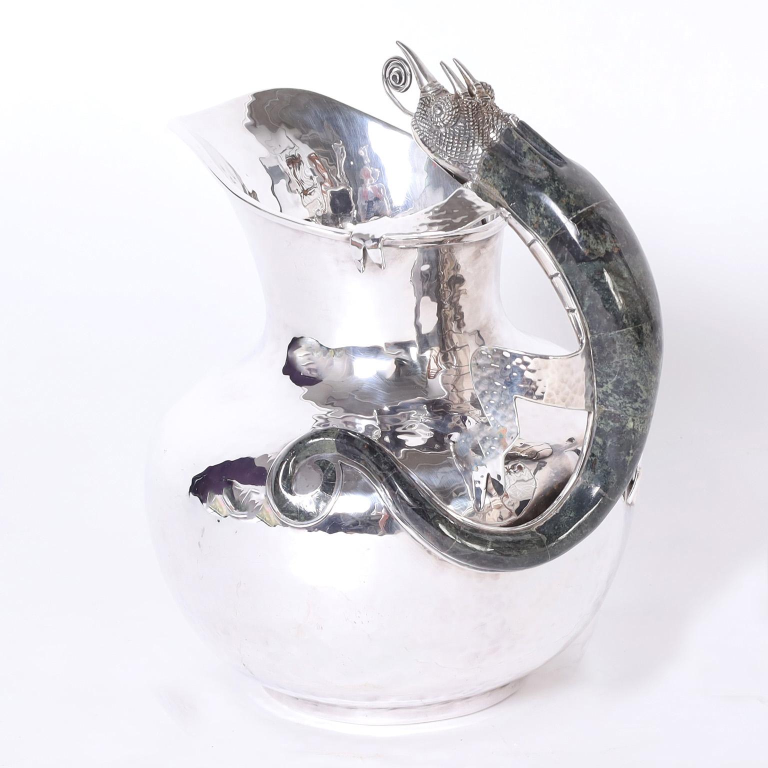 Mid-century water pitcher hand crafted by master silversmiths in silver plate over hammered copper featuring a chameleon clad in stone as a handle. Stamped Los Castillo on the bottom.
